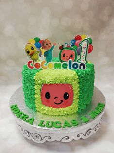 a birthday cake with an image of a cartoon character on the front and green frosting that says cocomelon