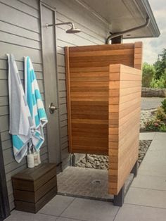 the outside of a house with towels hanging on it's wall and an open shower door