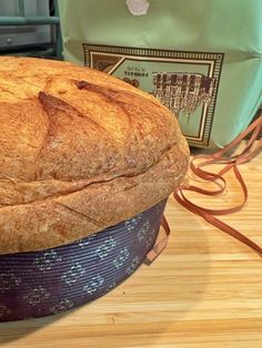 a loaf of bread sitting on top of a wooden table next to an apple bag