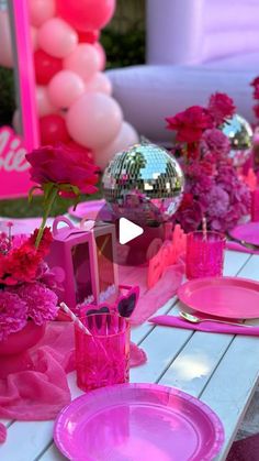 the table is set with pink plates and flowers