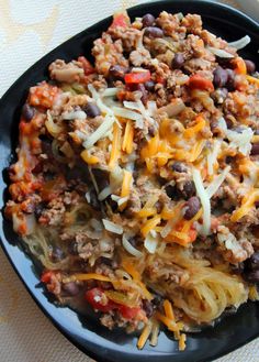 a black plate topped with taco salad and cheese