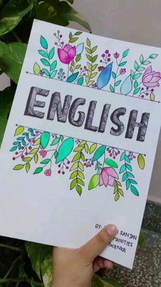 a person holding up a sign that says english with flowers and leaves on the front