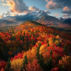 the mountain is surrounded by colorful trees and mountains with snow capped peaks in the distance