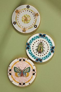 three plates with designs on them sitting next to each other in front of a green wall