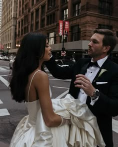 a man in a tuxedo holds the hand of a woman in a wedding dress