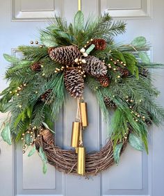 a wreath with pine cones, evergreen leaves and bells hanging on the front door for christmas