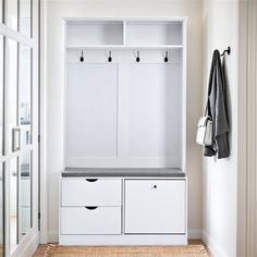 an entryway with white storage cabinets and drawers