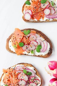 three slices of bread with salmon, radishes and cucumbers on them