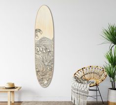 a surfboard hanging on the wall next to a wicker chair and potted plant