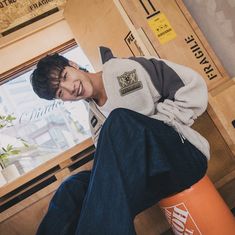 a young man sitting on top of an orange barrel