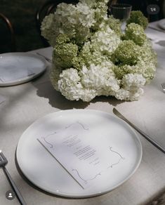 a white plate sitting on top of a table next to silver utensils and flowers