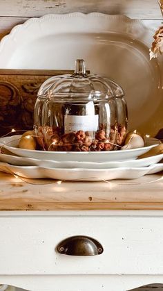 a glass covered dish on top of a white dresser