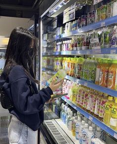 a woman is looking at some drinks on the shelf