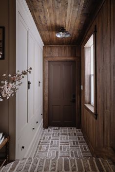 a hallway with wood paneling and tile flooring next to a door in a home