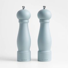 two salt and pepper shakers sitting side by side on a white surface, one is light blue