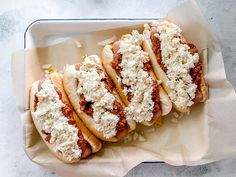 four hot dogs with toppings in a tray on a counter top, ready to be eaten