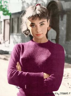 an old photo of a woman in a purple sweater with her arms crossed and looking at the camera