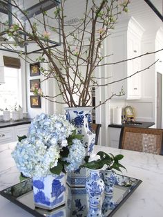 a table with blue and white vases sitting on top of it next to a tree