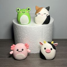 three small toy animals sitting on top of a roll of toilet paper next to each other