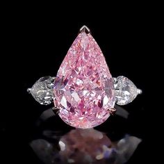 a pink diamond with three white diamonds on it's side and the center stone is surrounded