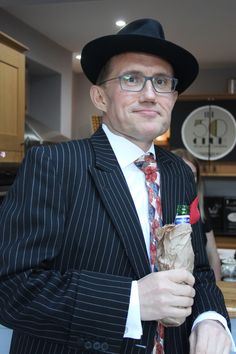 a man in a suit and tie holding a bottle with a red cap on it