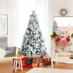 a living room with a christmas tree and presents on the floor in front of it