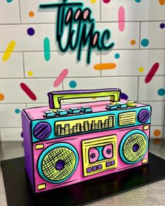 a pink boombox sitting on top of a table next to a wall with confetti sprinkles