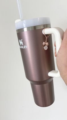 a person is holding a coffee cup with a keychain attached to the handle