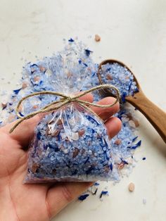 a hand holding a bag filled with blue and white confetti next to a wooden spoon