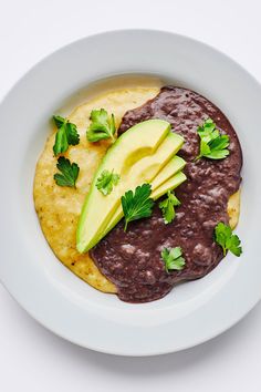 a white plate topped with black beans and an avocado