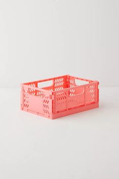 a pink plastic crate sitting on top of a white table next to an orange container