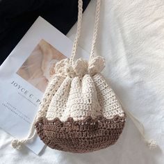 a crocheted purse sitting on top of a bed next to a book and magazine