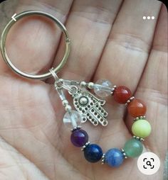 a hand holding a keychain with seven chakrah beads on the end