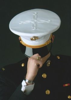 a man in uniform adjusts his hat