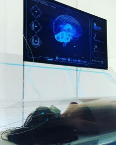 a person laying on the ground in front of a computer screen with a brain scan on it