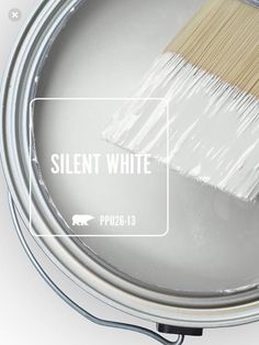 a paint can filled with white paint next to a brush on top of the tin