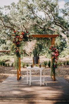 an outdoor ceremony setup with flowers and greenery on the table, surrounded by trees