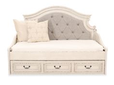 a white daybed with drawers underneath it and two pillows on the top of it