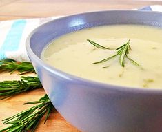 a blue bowl filled with soup on top of a wooden table next to a napkin