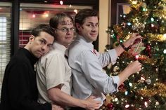 three men standing in front of a christmas tree