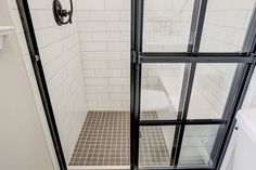 Master bathroom remodel includes glass shower doors with matte-black grids, enclosing an all-tile shower that features a bench seat and Caribbean-blue tiled niche, swarm gray vanity with white marble top, distressed vinyl plank floor, and floating live-edge wood shelving