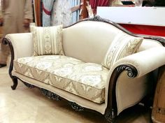 a white couch sitting on top of a hard wood floor next to a red table