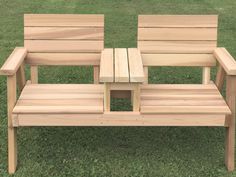 a wooden bench sitting on top of a lush green field next to a small table