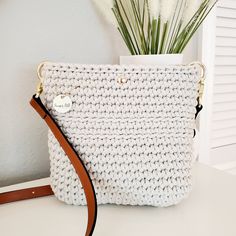 This charming boho crossbody bag is petite yet roomy.  It's just the right size to hold your everyday essentials for a fuss-free day out.  It is lightweight at 15 ounces empty, with a perfect adjustable leather strap. Lovingly crocheted by hand, this bag is one of a kind. Whether you're stepping out for a casual outing or headed to a chic brunch, this small crossbody bag is ready to compliment any outfit with charm.  This bag is extremely durable and eco-friendly, crocheted with 100% recycled 5mm cotton cord.  The brown leather strap is adjustable and the bag includes a magnetic snap closure.   COLORS This beautiful crossbody bag is available in beige with adjustable brown leather strap.  MEASUREMENTS 8 INCHES HIGH 8 INCHES WIDE STRAP  IS ADJUSTABLE from 43 inches to 51 inches in length MA Cream Crochet Clutch Bag For Everyday Use, Chic Handmade Crossbody Bucket Bag, Everyday Crochet Crossbody Bag With Removable Pouch, Handmade Crossbody Bag For On-the-go, Handmade Beige Shoulder Bag For On-the-go, Handmade Crochet Crossbody Bag For Gift, Handmade Crossbody Crochet Bag For Gift, Handmade Cream Crossbody Bag, Chic Handmade Cream Crossbody Bag