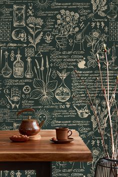 a wooden table topped with a tea pot next to a vase filled with flowers and plants