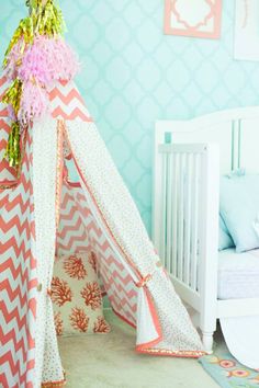 a pink and white teepee with flowers on it in the corner of a child's room