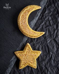 two gold stars and a moon on black paper