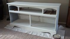 a white entertainment center sitting on top of a floor next to a can of paint