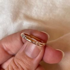 a person holding a gold ring with diamonds on it's side and the other hand