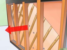 a red arrow pointing to the side of a room with wooden framing and insulation in it